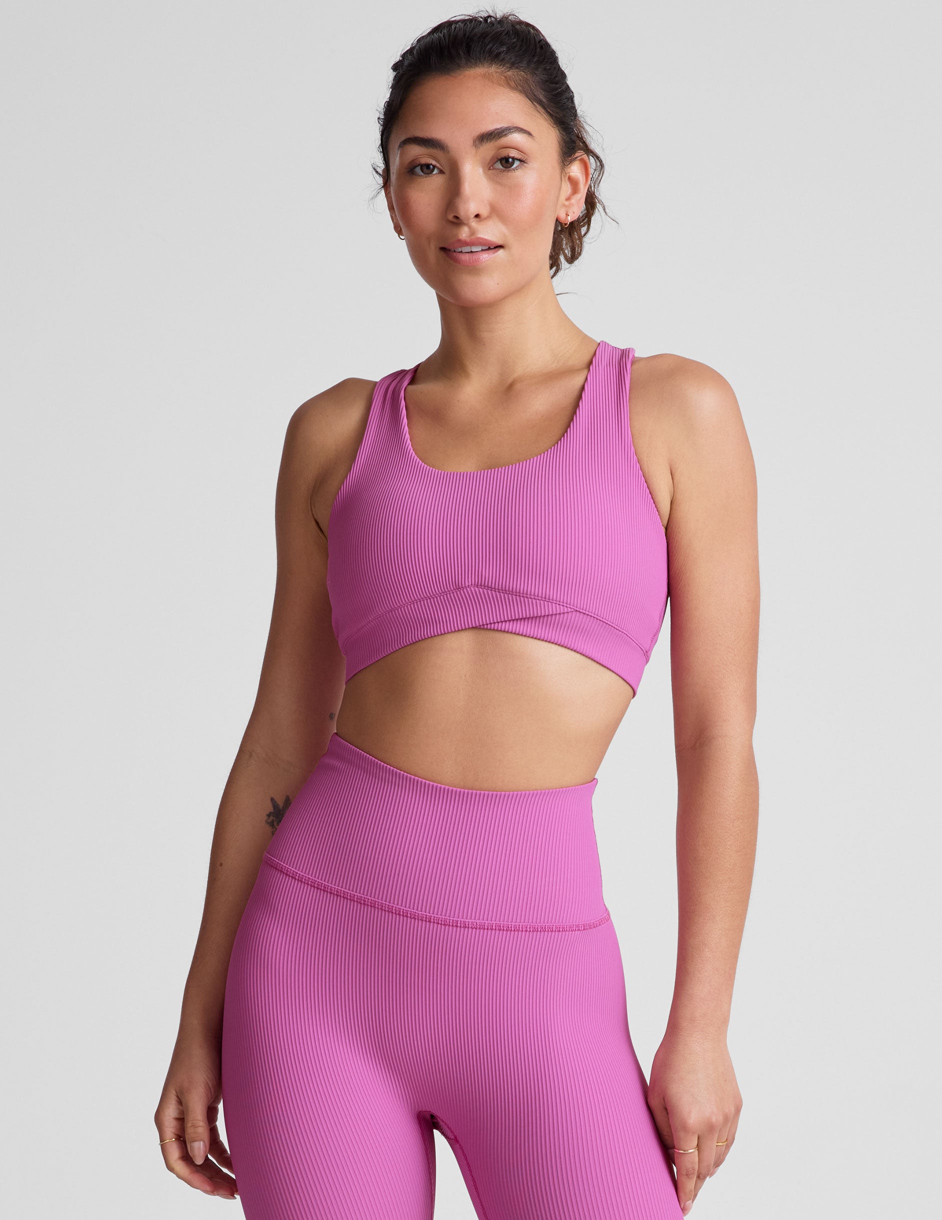 pink medium support racerback bra with a scoop neckline, overlapping hemband detail, is lined with performance lining and powermesh in between, and has removable bra pads.