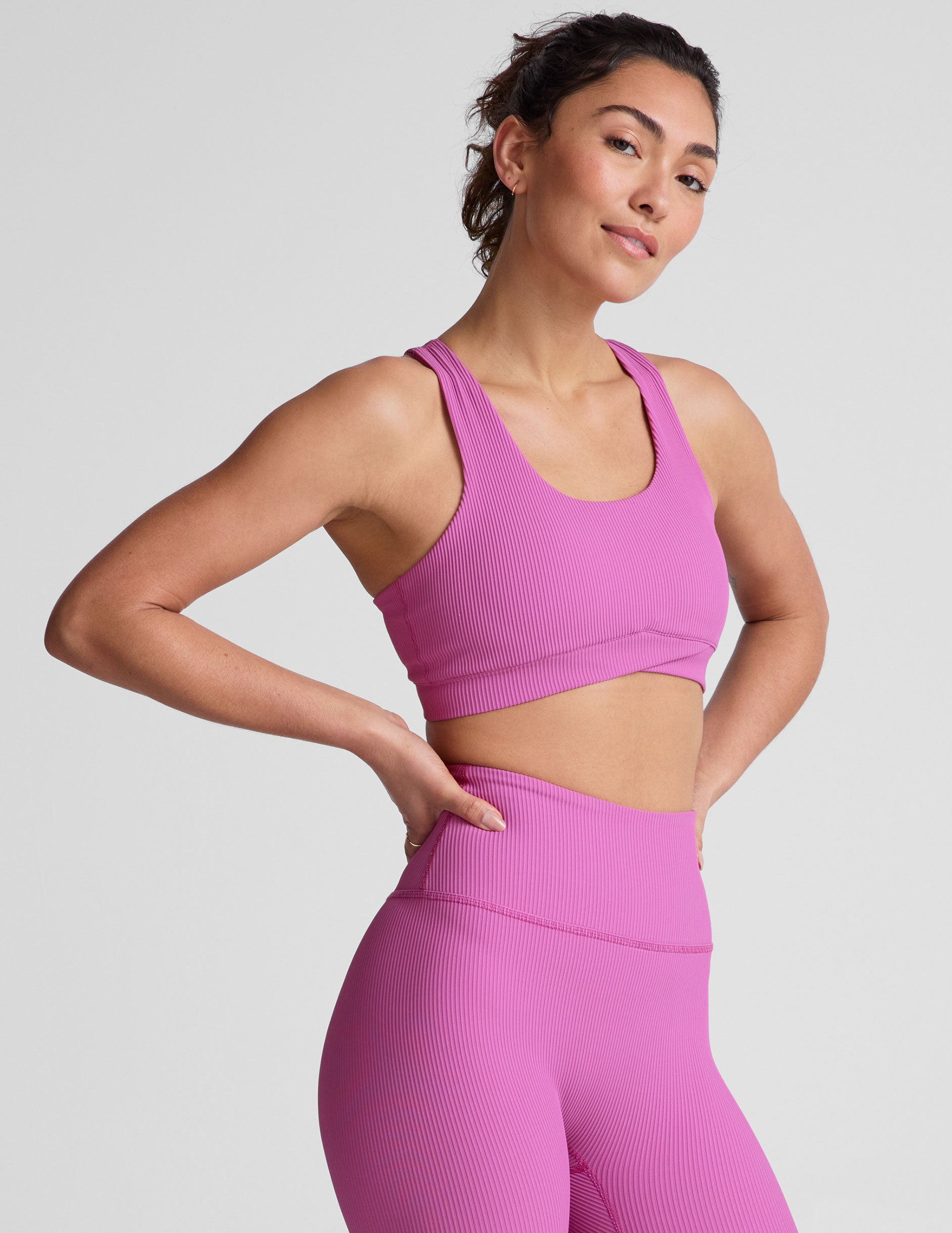 pink medium support racerback bra with a scoop neckline, overlapping hemband detail, is lined with performance lining and powermesh in between, and has removable bra pads.