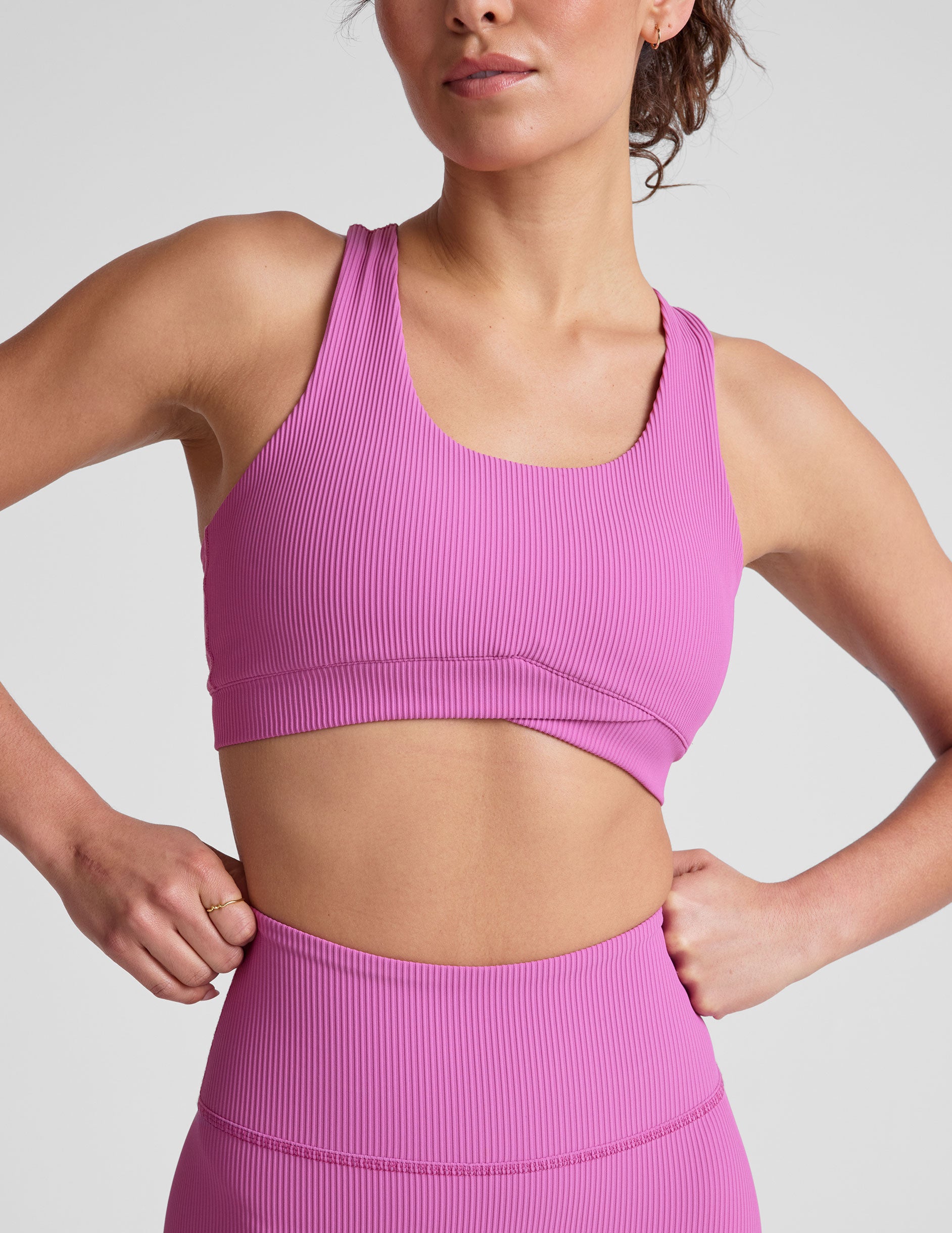 pink medium support racerback bra with a scoop neckline, overlapping hemband detail, is lined with performance lining and powermesh in between, and has removable bra pads.