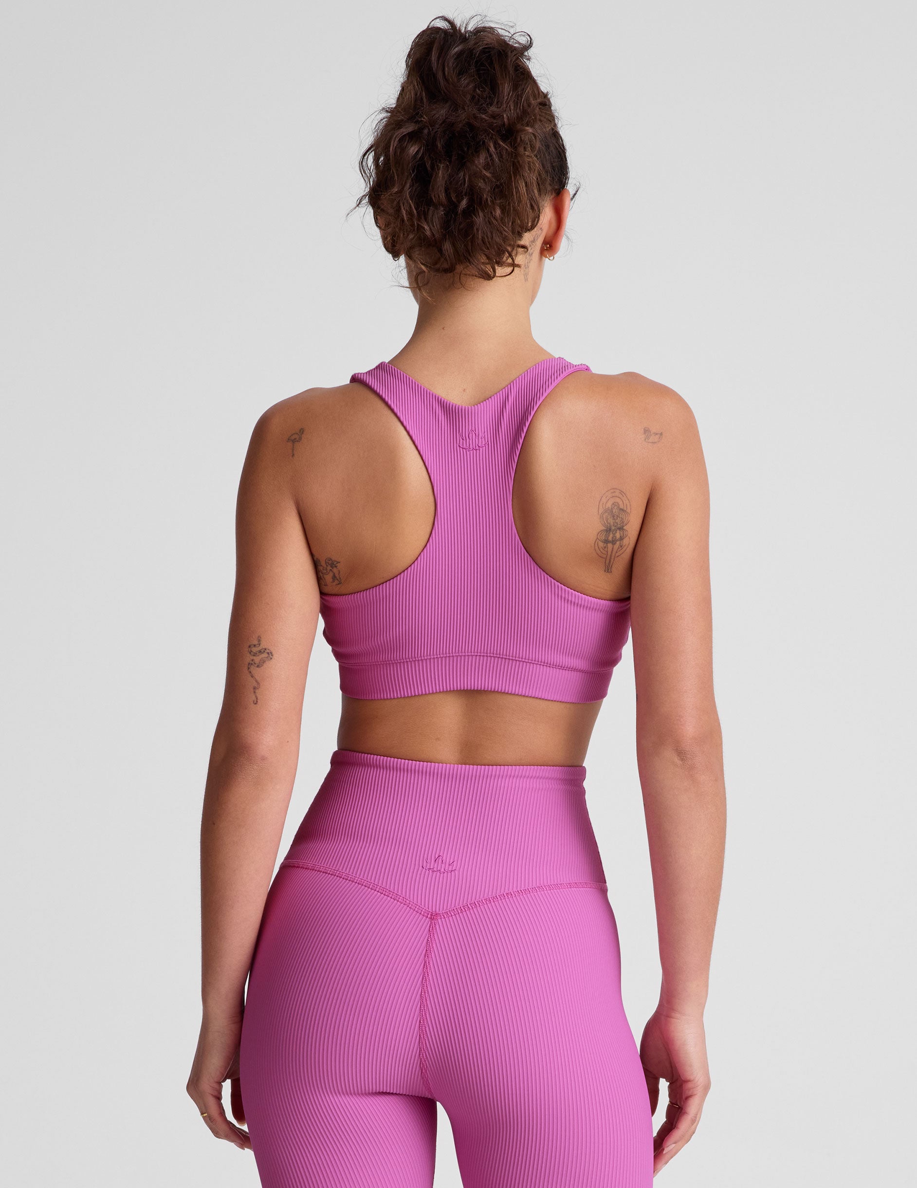 pink medium support racerback bra with a scoop neckline, overlapping hemband detail, is lined with performance lining and powermesh in between, and has removable bra pads.