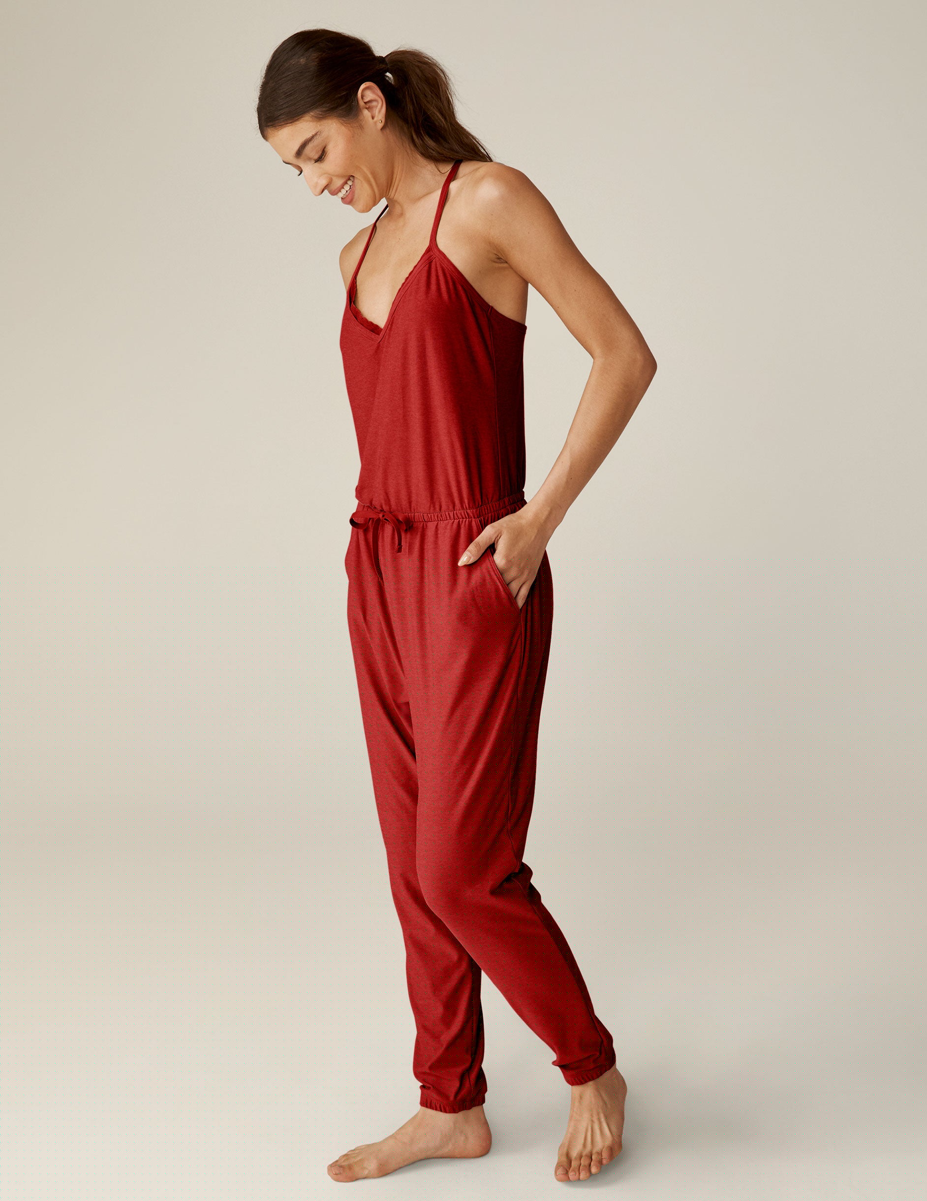 red racerback jogger jumpsuit with scalloped lace detailing on the neckline and a drawstring at waist.