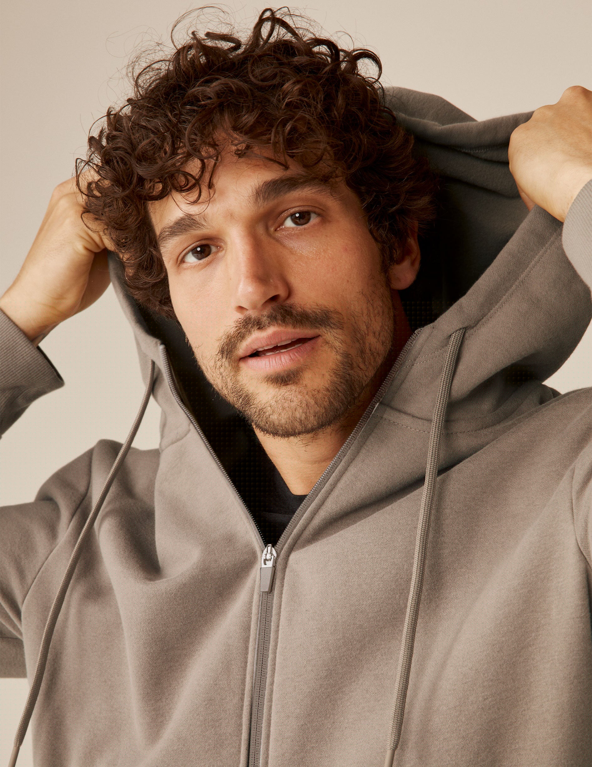 model is wearing a brown men's zip-up hooded jacket.