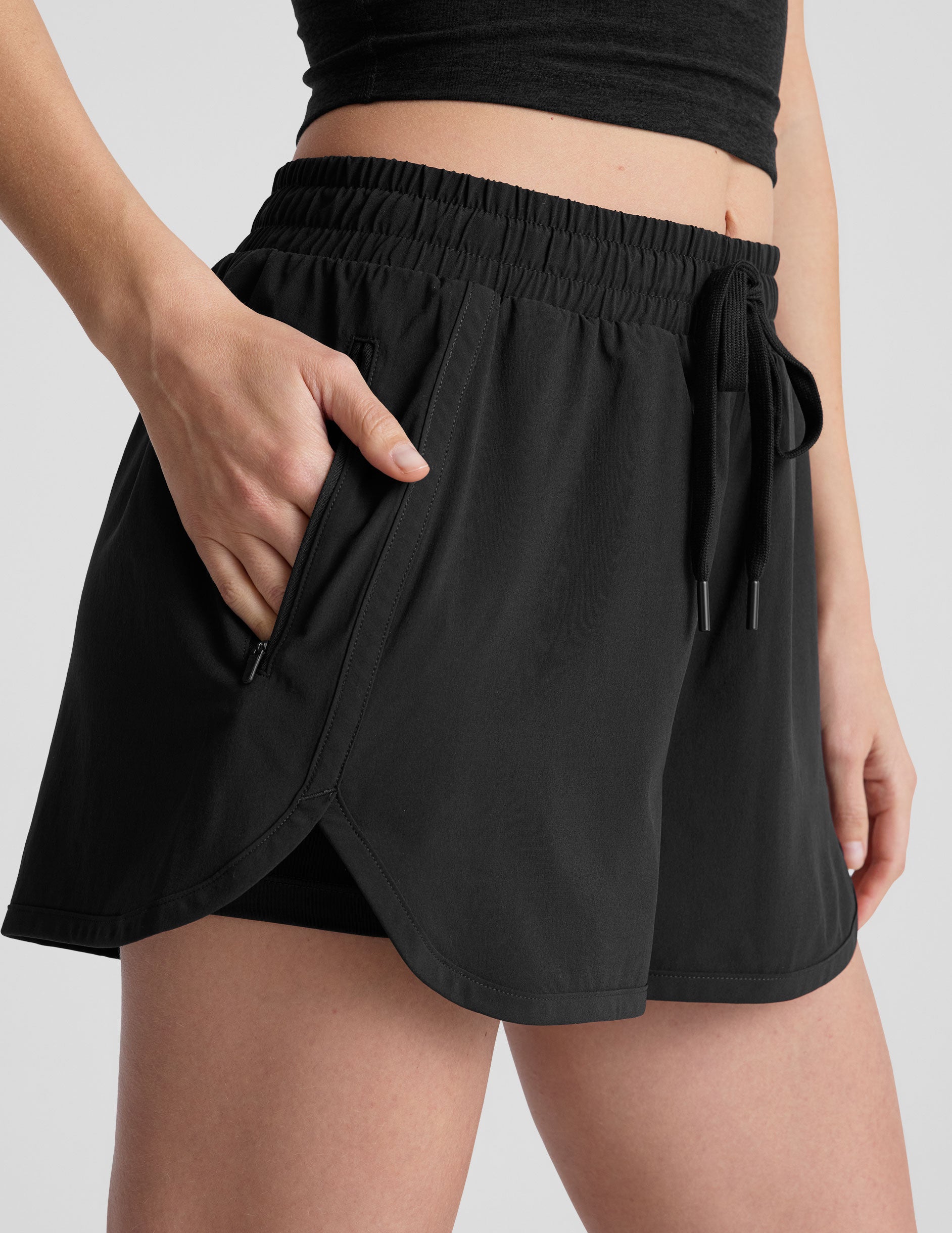 black shorts with a 2.5" inseam, encased elastic at waistband with drawcord, self binding at hem edges, side zipper pockets, and interior performance lining shorts.