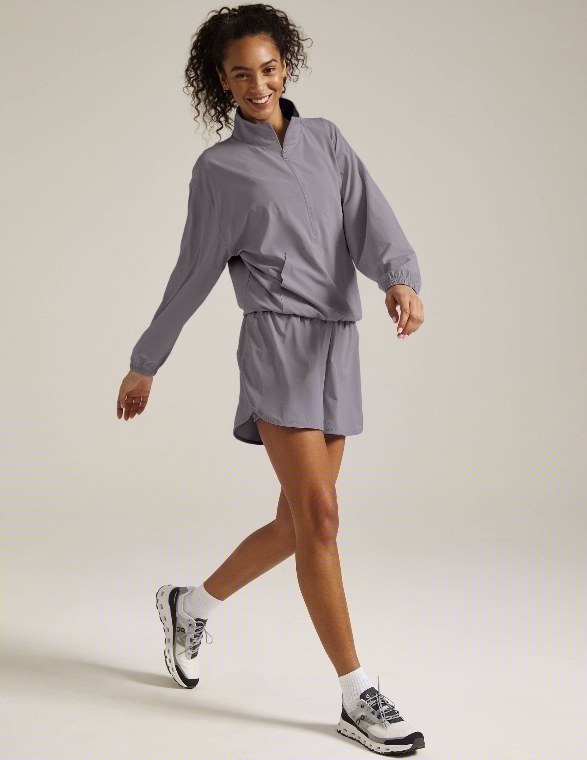 model is wearing a gray quarter zip jacket with a kangaroo pocket.