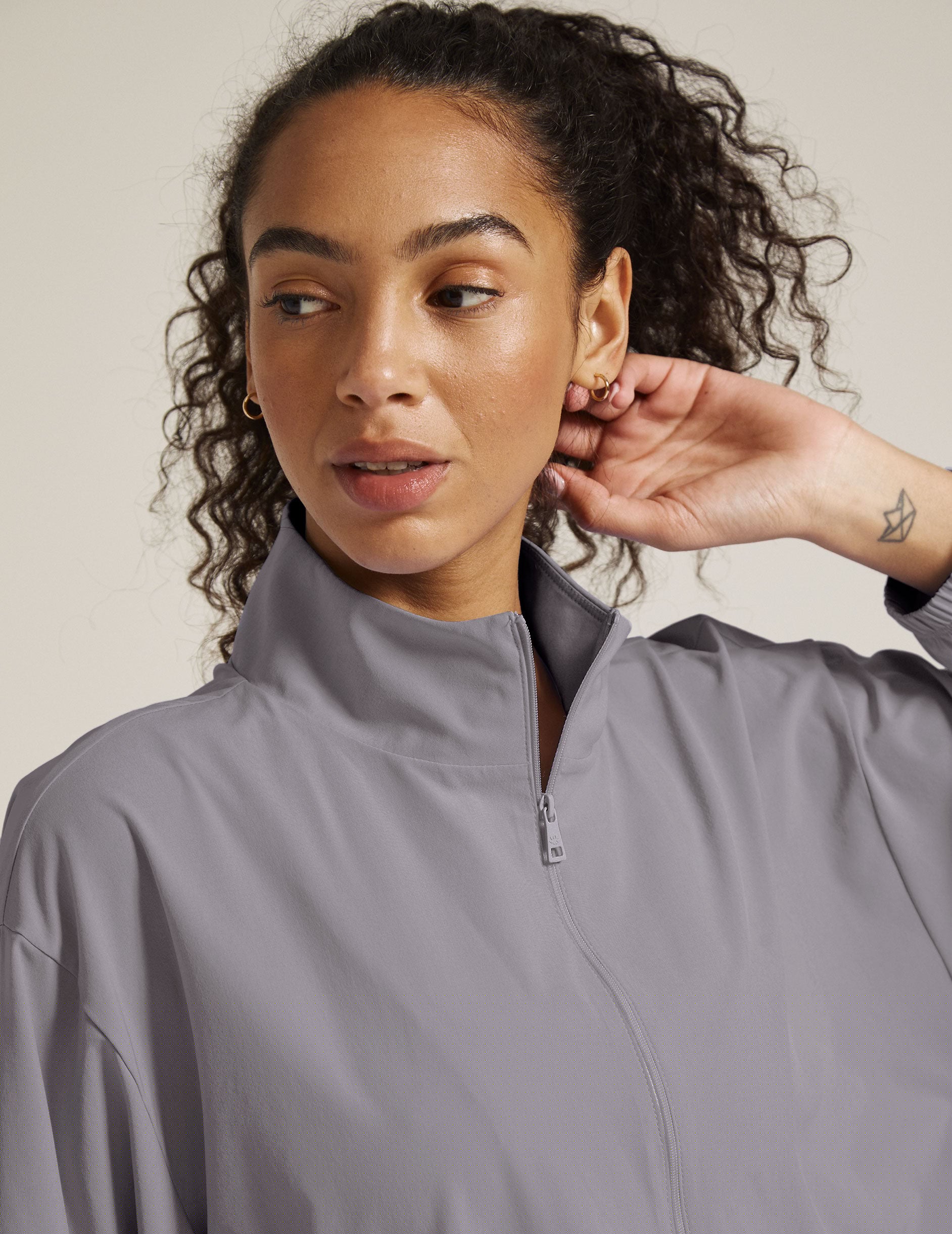 model is wearing a gray quarter zip jacket with a kangaroo pocket.