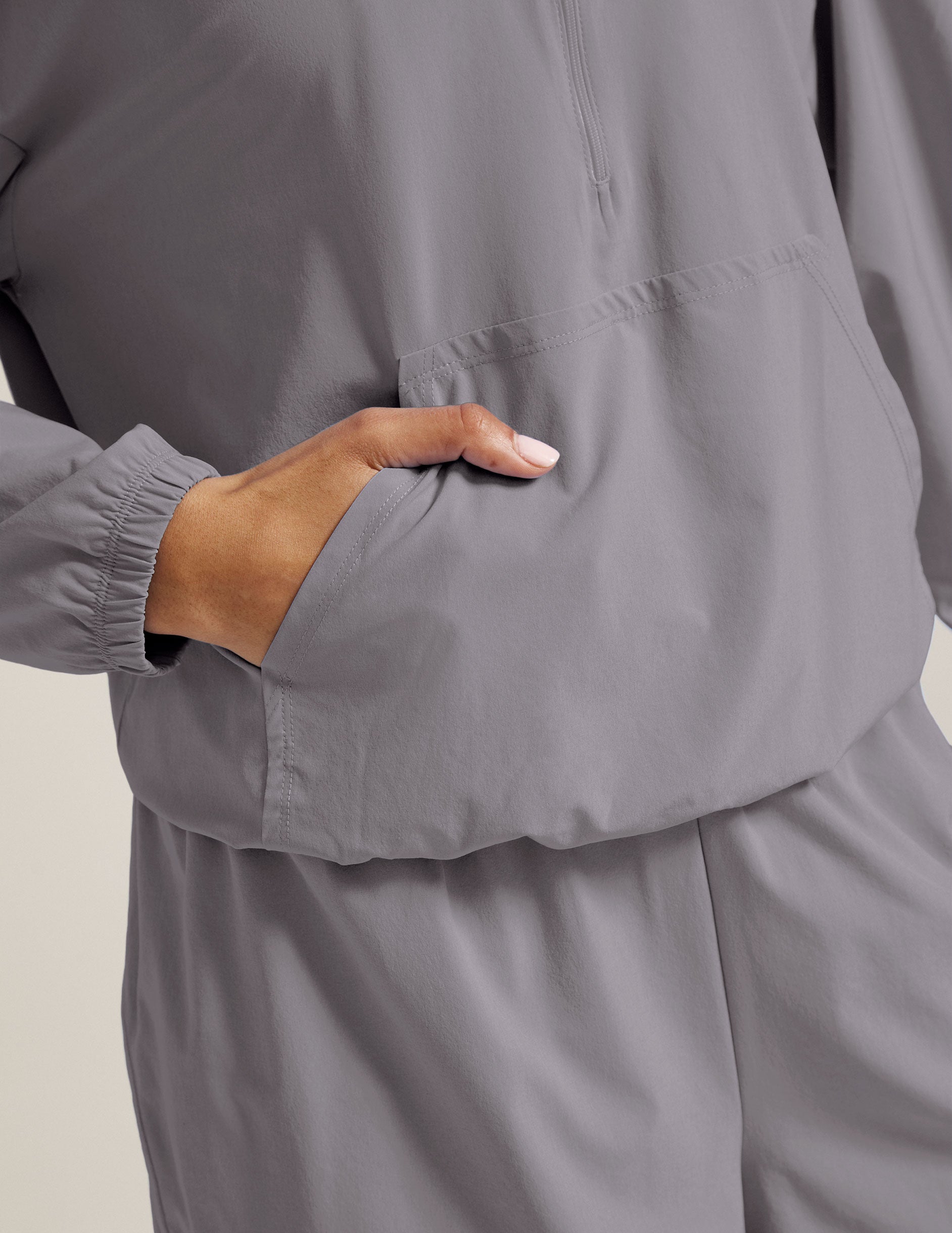 model is wearing a gray quarter zip jacket with a kangaroo pocket.