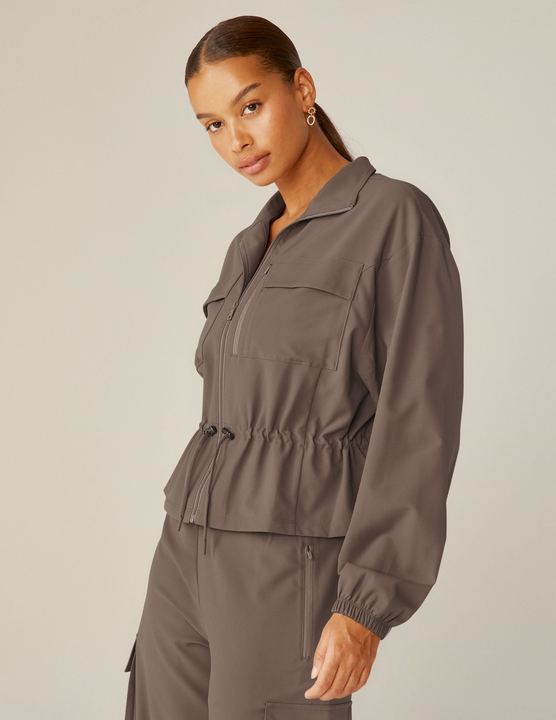 brown cargo style zip-up jacket with a drawstring tie at waist and pockets.