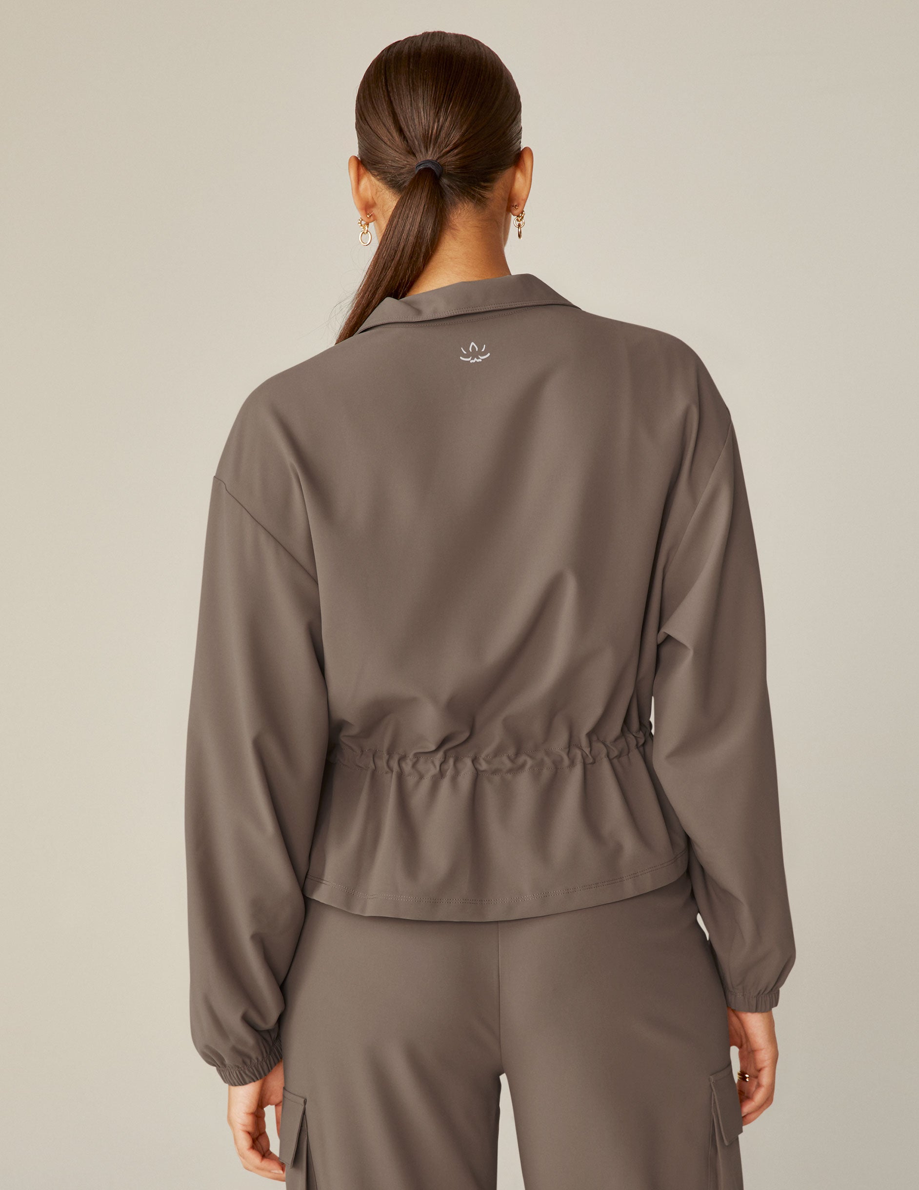brown cargo style zip-up jacket with a drawstring tie at waist and pockets.