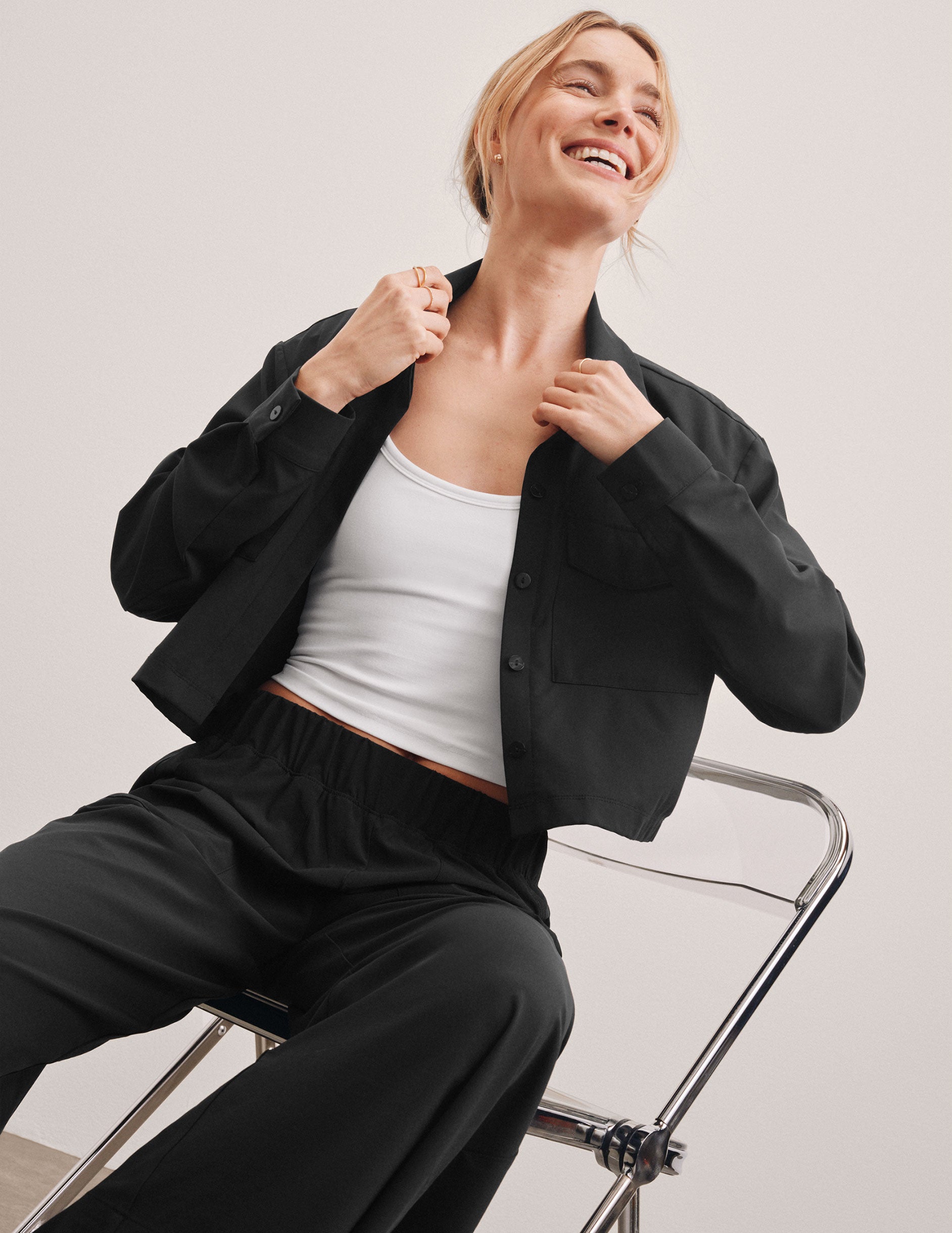 black cropped loose fitting jacket with a collar at neckline, hidden placket with button closure at center front, and front chest cargo pockets.