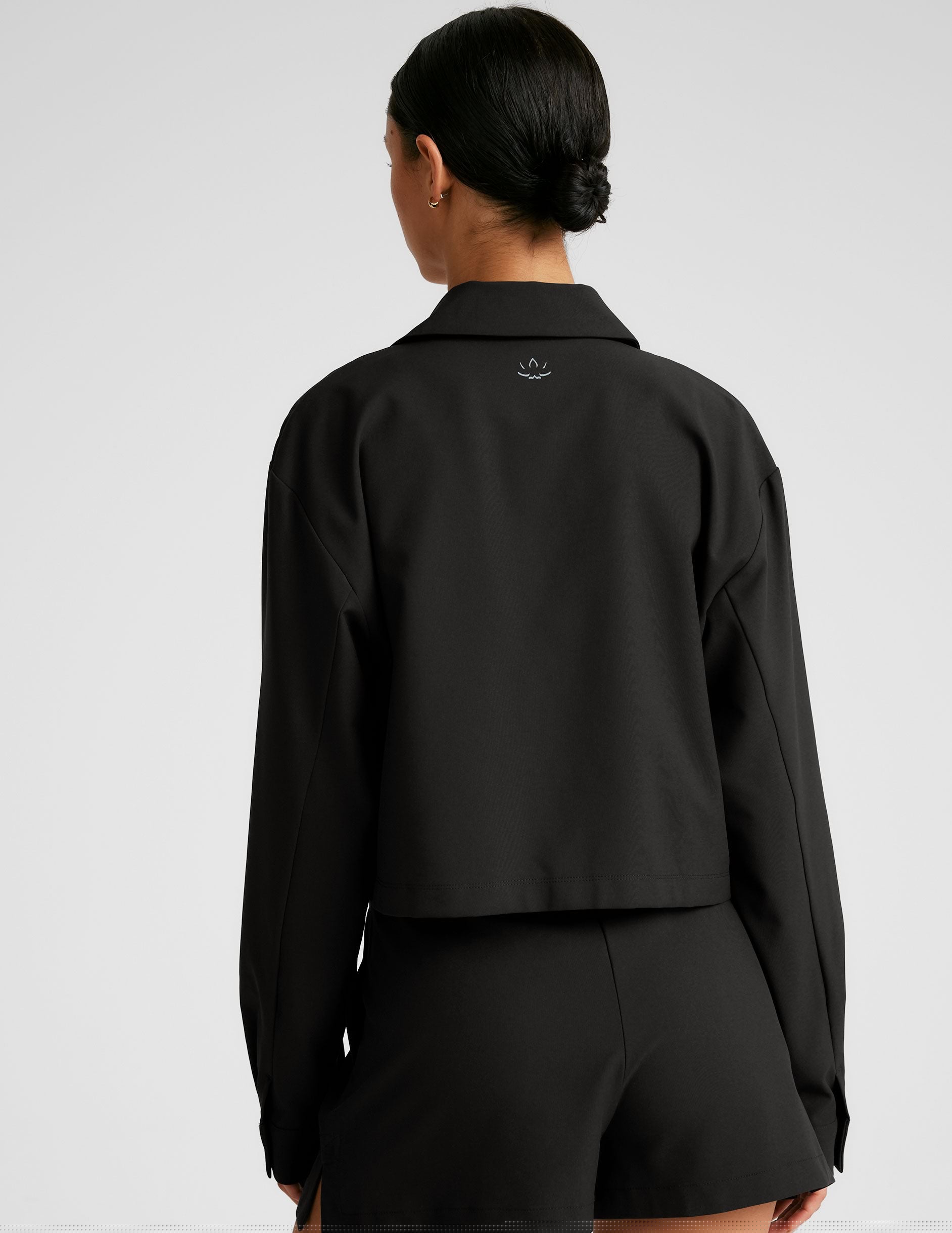 black cropped loose fitting jacket with a collar at neckline, hidden placket with button closure at center front, and front chest cargo pockets.