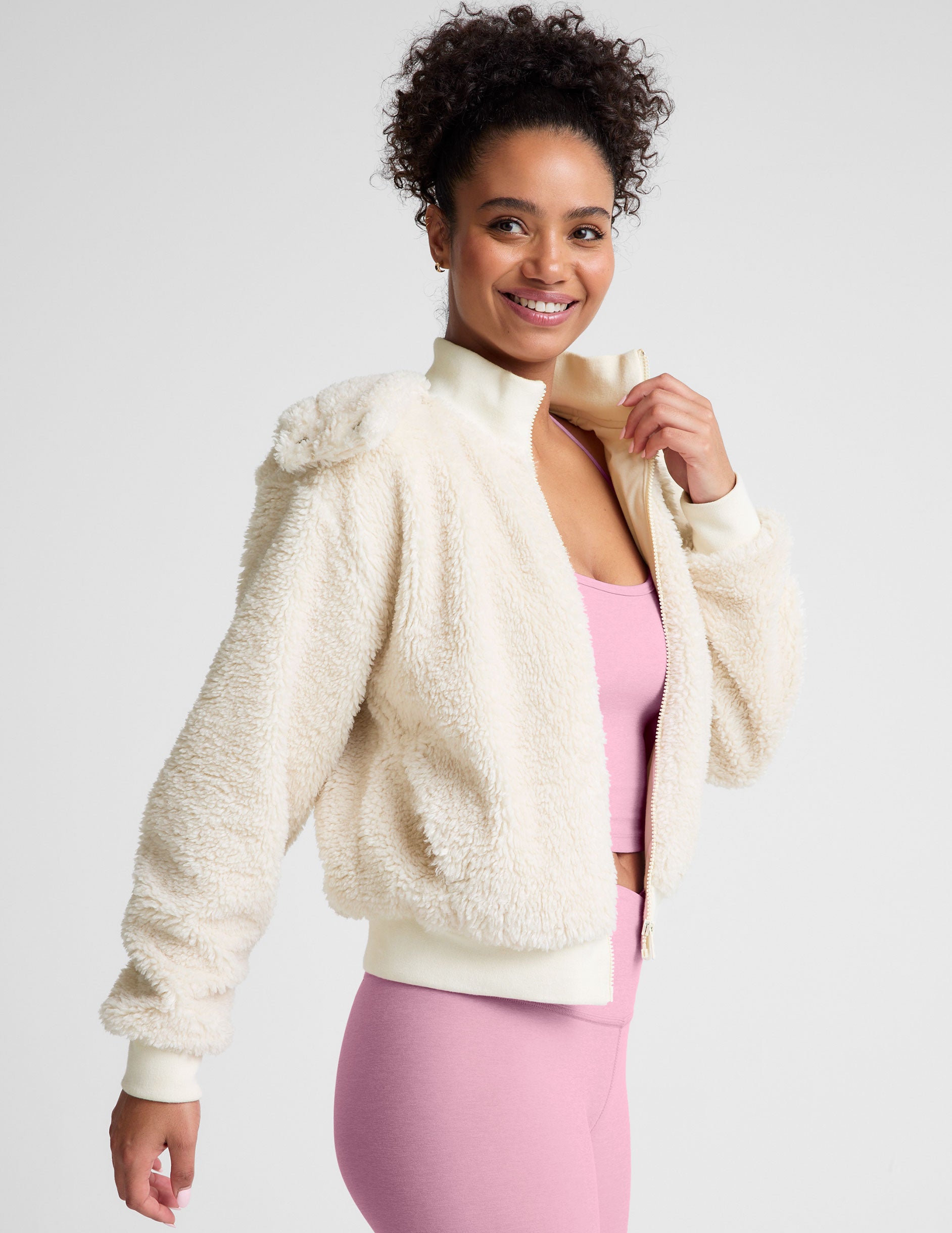 white zip-up hooded faux sherpa jacket with pockets.