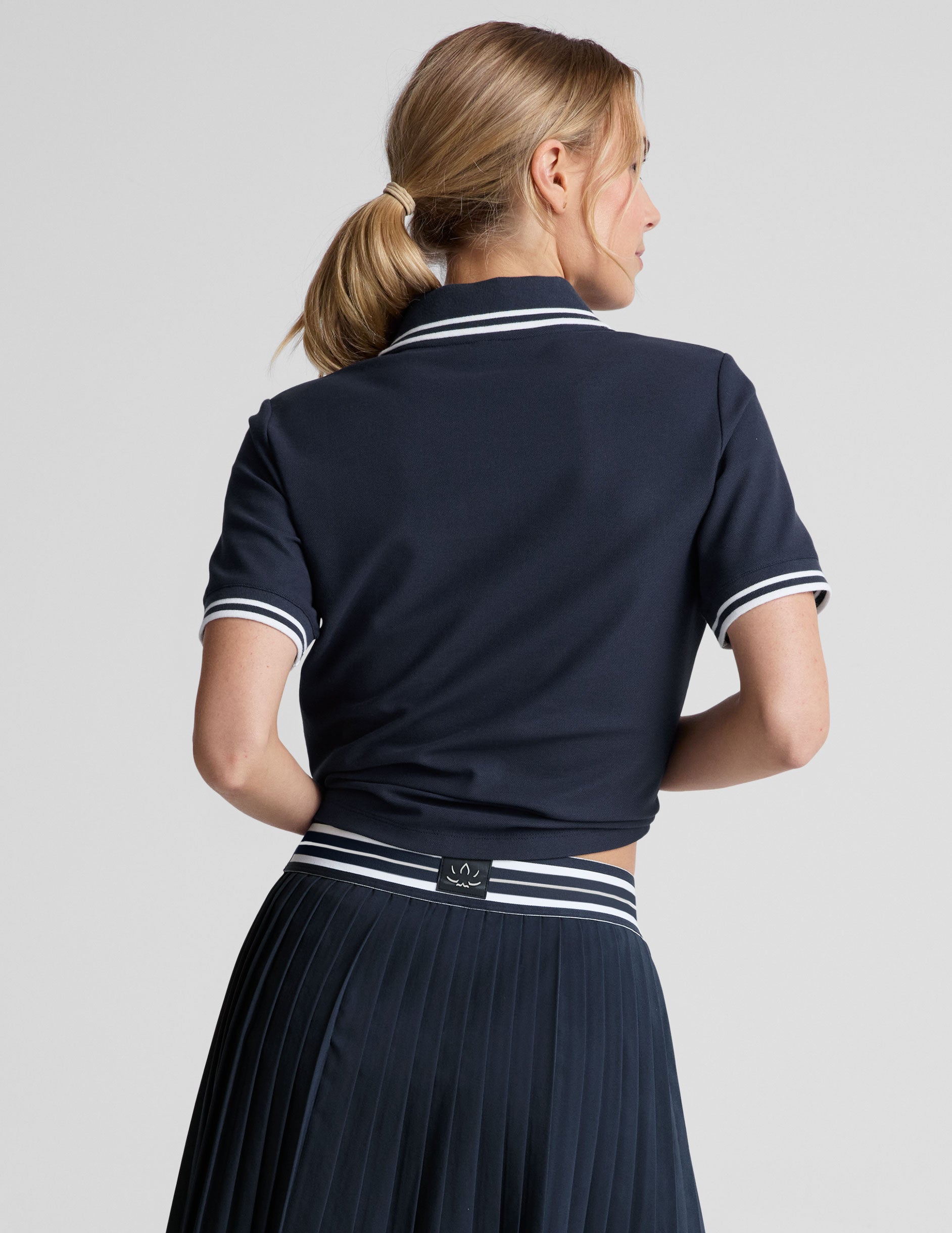 white fitted polo style short sleeve t-shirt with a stripe rib collar and cuff, front placket with buttons, and side slits.