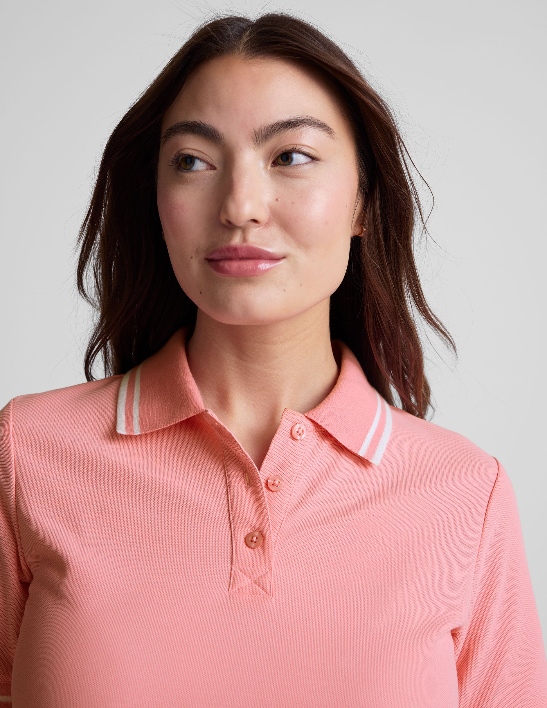 pink polo style top with a stripe rib collar and cuff , front placket with buttons, side slits, and hits at a high hip length.