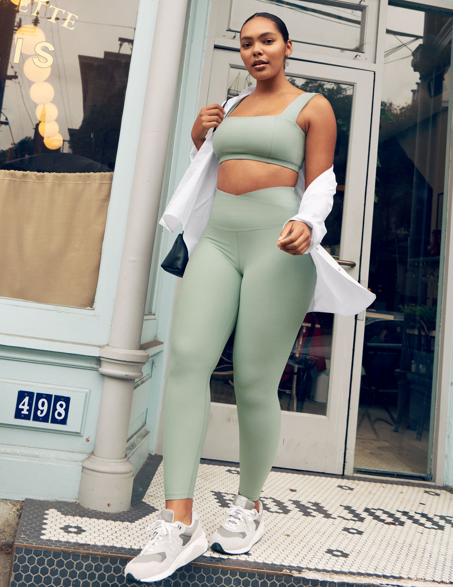 green high-waisted midi leggings with a front crossover detail on the waistband.