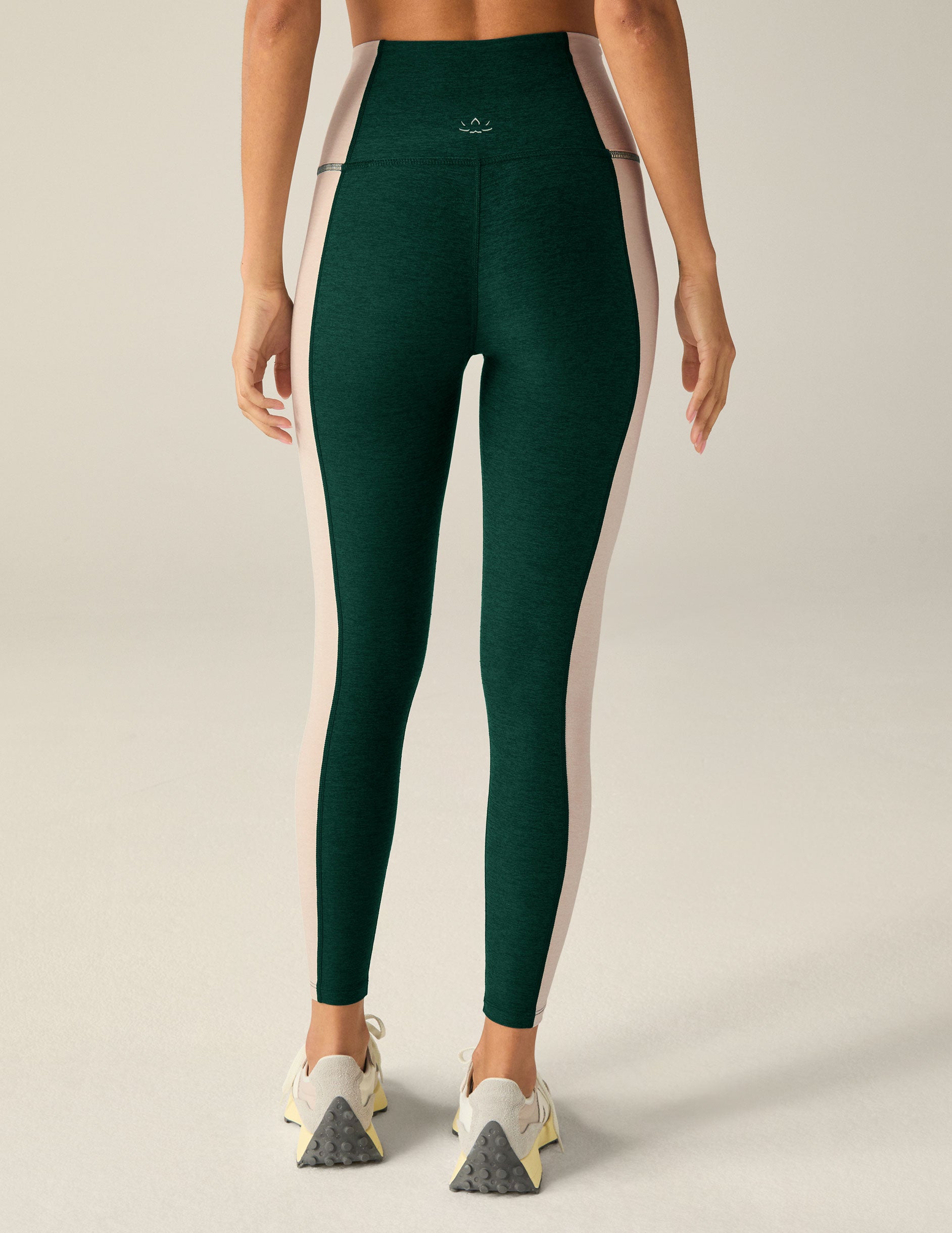 green high-waisted midi leggings with eggshell colored outlining down the sides.