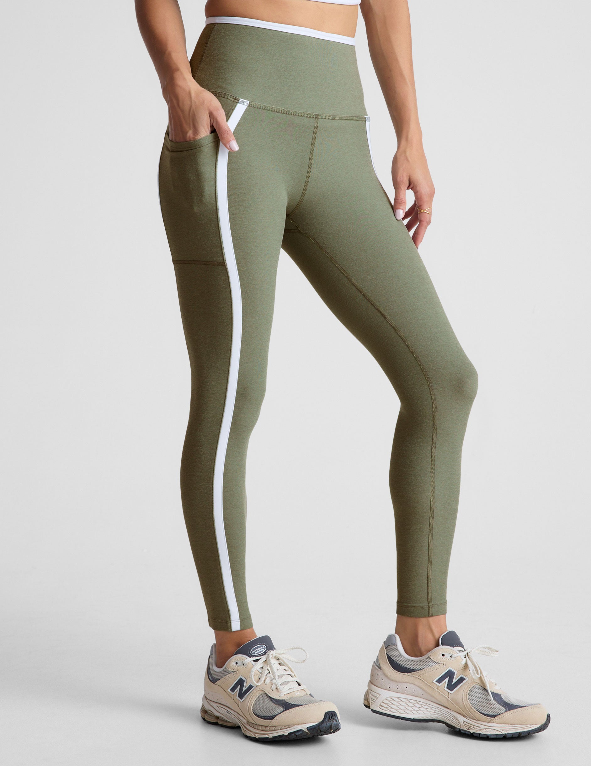green high-waisted midi length legging with side pockets and white piping.