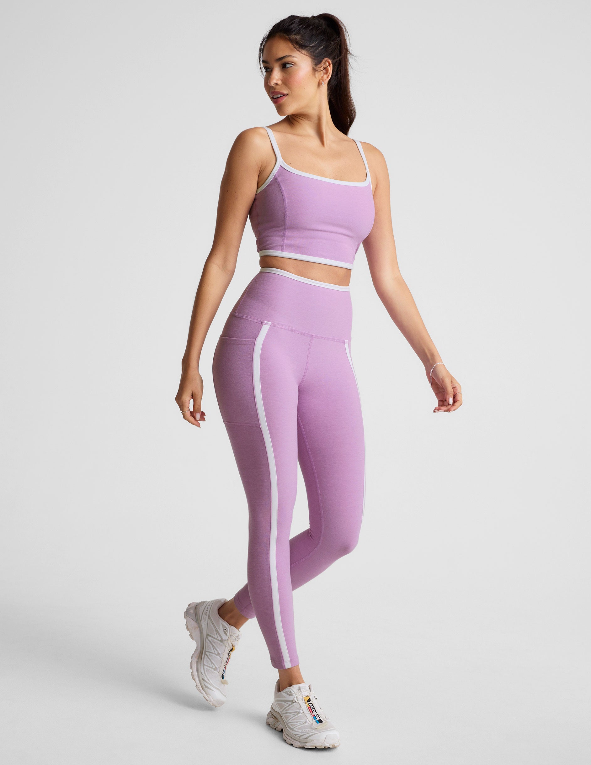 purple high-waisted midi length legging with pockets and white piping.