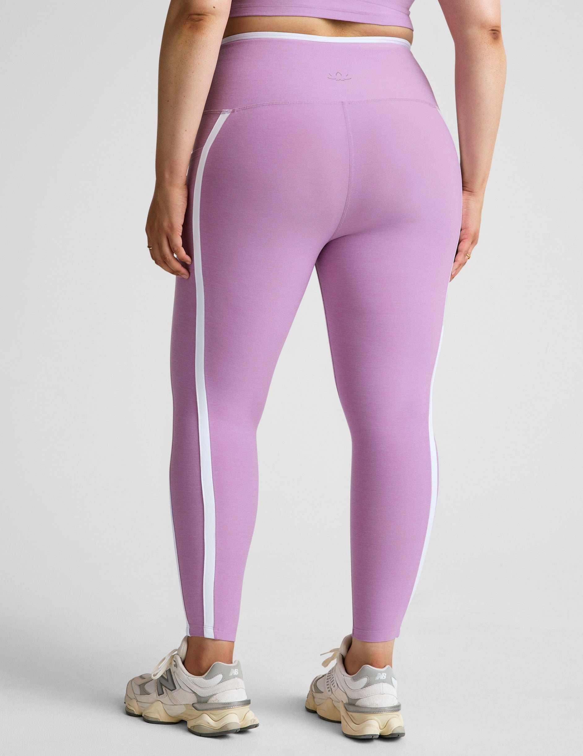 purple high-waisted midi length legging with pockets and white piping.