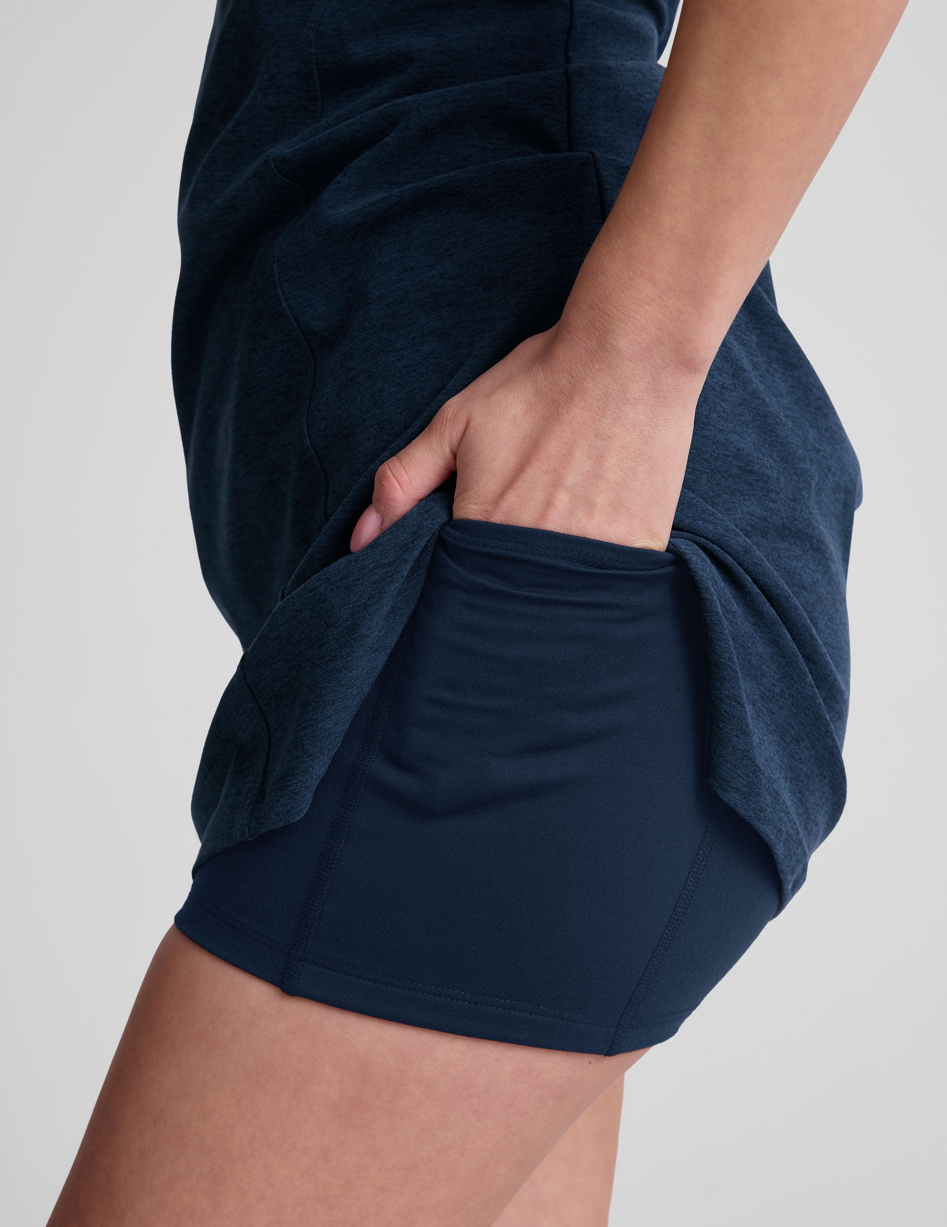 navy blue mini length dress with a front V neckline, back keyhole detail, contrast binding at neckline and arm openings, and an Interior bodysuit with pockets.