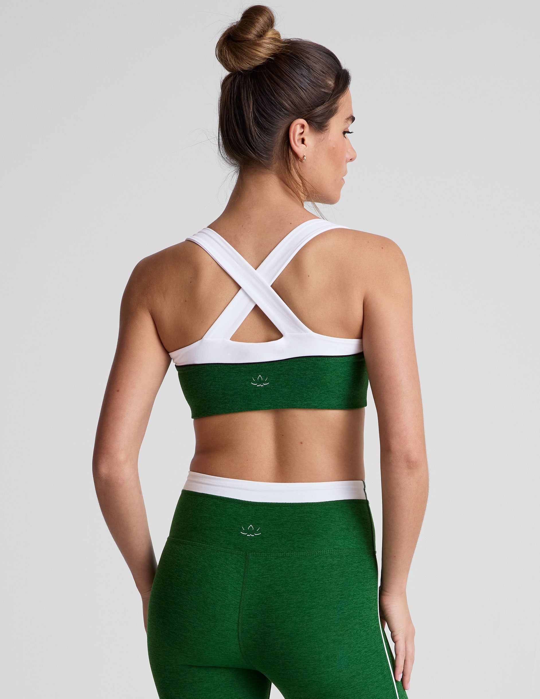 back view of green self-lined, medium to low support bra top with a colorblock sweetheart neckline panel, contrast straps, and princess seams. bra is paired with green high-waisted midi leggings with a white contrast trim around waistband and down sides of legs.