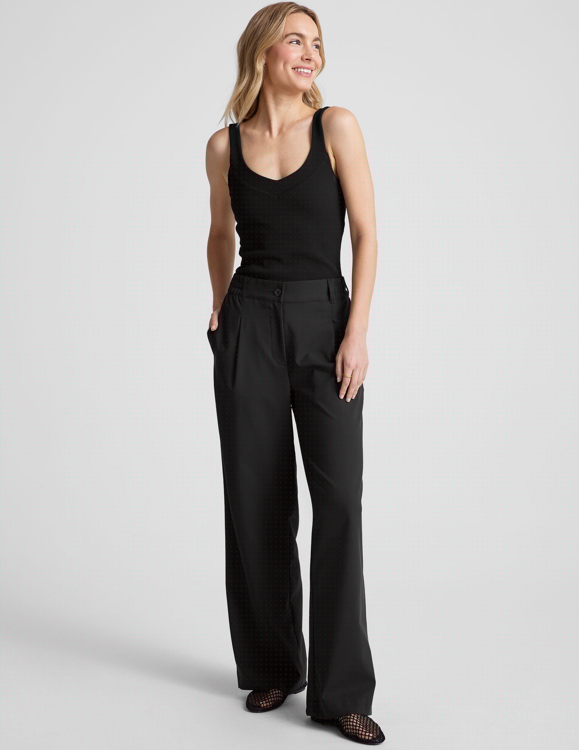 black ribbed tank top with a soft V neckline front and back​, overlapping front neckline detail, and a performance lining shelf bra. Tank hits at a high hip length. 