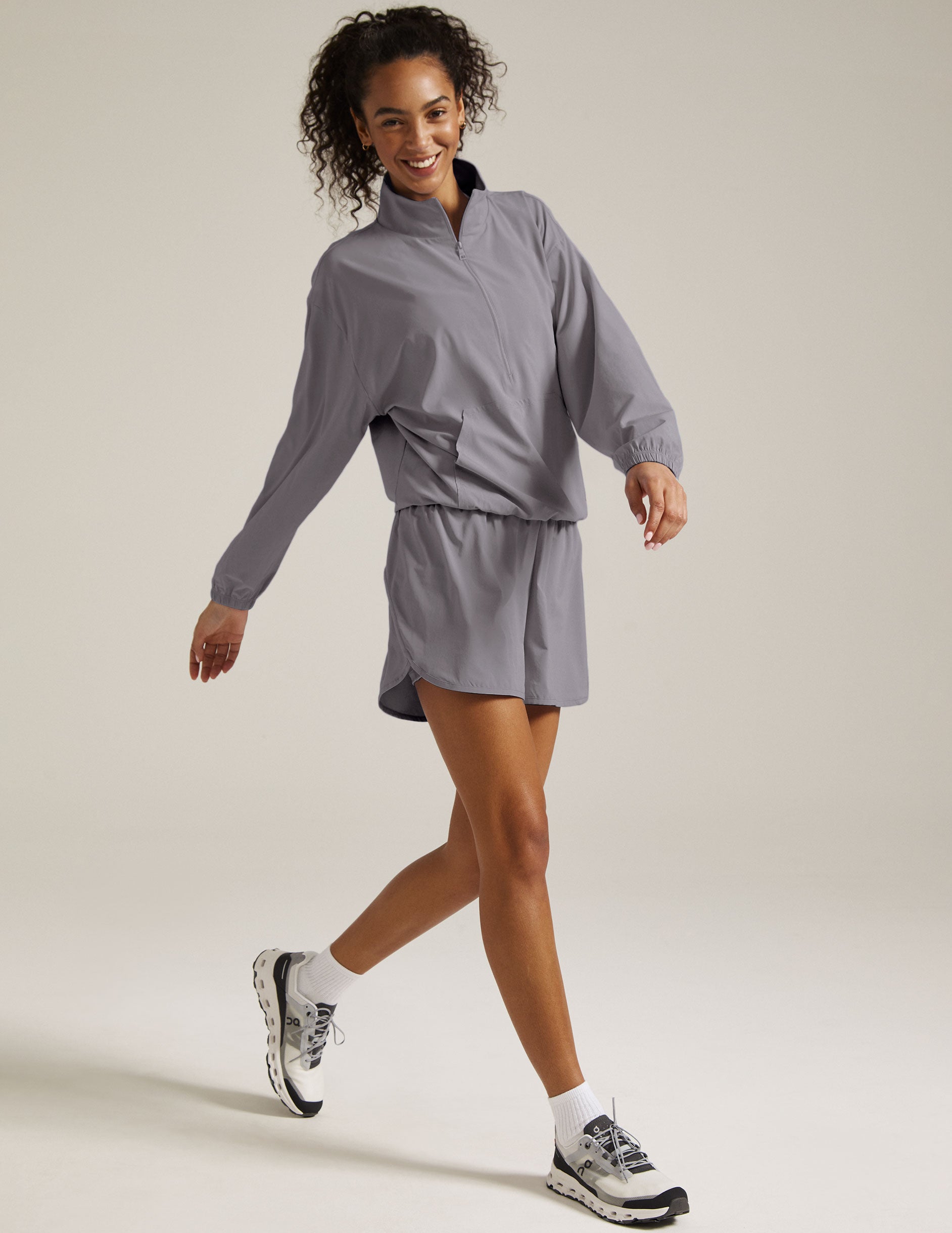 model is wearing a gray quarter zip jacket with a kangaroo pocket. 